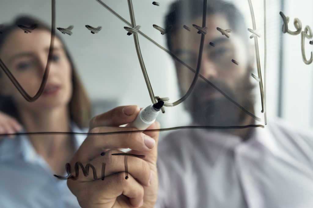 close up man explaining business analytics his female colleague with graph whiteboard